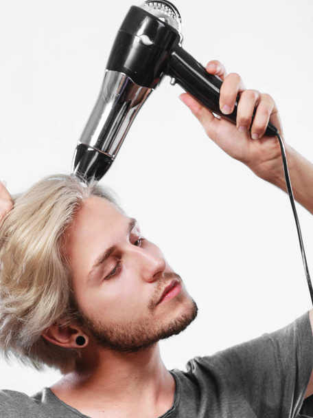Young man drying hair with hairdryer - Φωτογραφία, εικόνα