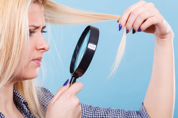 Woman looking at hair through magnifying glass - Valokuva, kuva