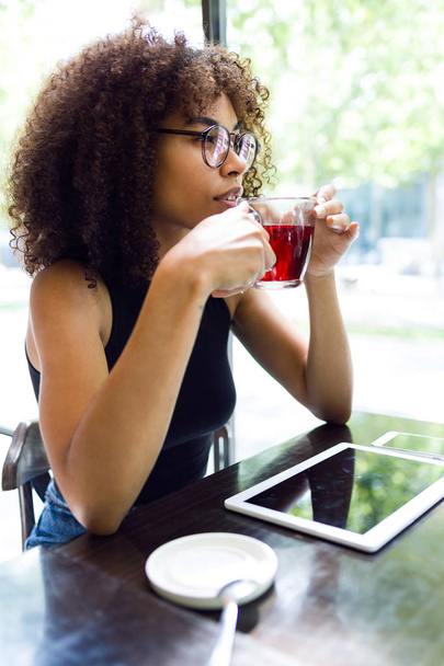 Gyönyörű fiatal nő, vörös teát iszik egy kávézóban. - Fotó, kép