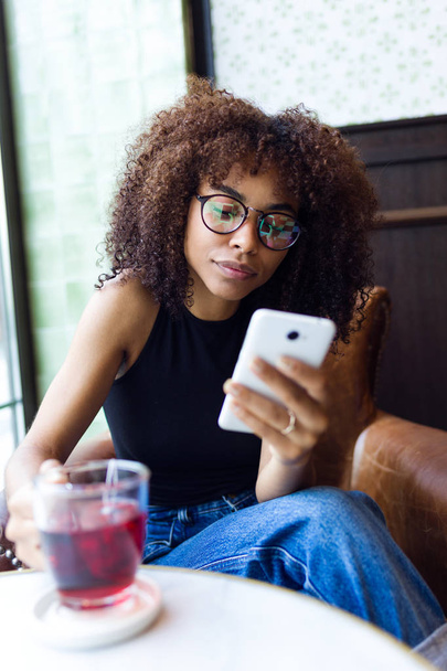 Красивая молодая женщина использует свой мобильный телефон в кафе
. - Фото, изображение
