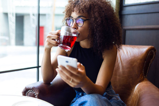 Beautiful young woman drinking red tea in cafe. - Foto, afbeelding