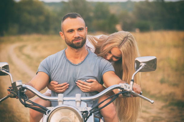 Young couple on a motorcycle in the field - 写真・画像