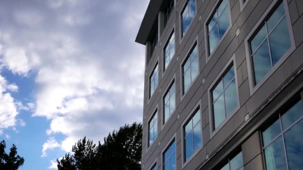 Moto di cielo nuvoloso con facciata in vetro riflesso illuminato su un moderno edificio per uffici
 - Filmati, video