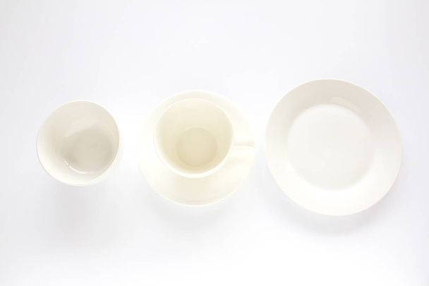 Пустая белая тарелка, белая чашка и белая чаша на белом фоне
 - Фото, изображение