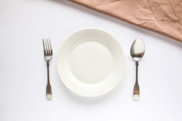 Біла тарілка зі срібною вилкою та ложкою
  - Фото, зображення