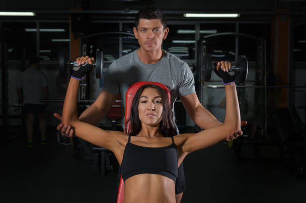 Couple exercises with dumbbells together in gym - Photo, Image
