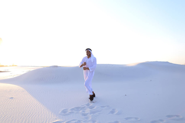 Уверенный мужчина, красивый араб в Кандуре ходит посреди белого
 - Фото, изображение