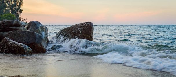 石に対して海の波しぶき - 写真・画像