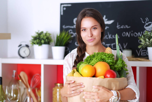 Young woman holding grocery shopping bag with vegetables - Foto, imagen