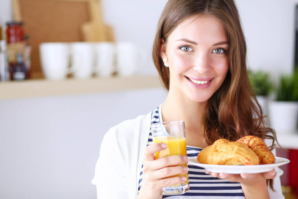 Young woman with glass of juice and cakes standing in kitchen - Foto, immagini