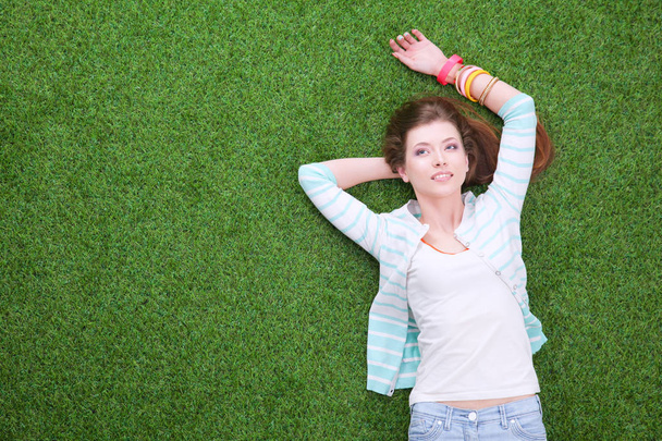 Beautiful redhead women lying down on green grass in summer time in the park - Fotó, kép