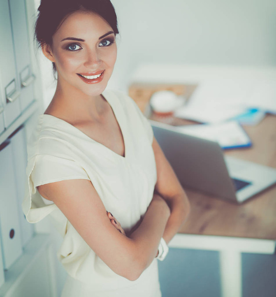Attractive businesswoman standing near wall in office - Фото, зображення