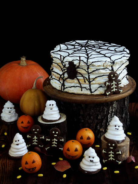 Drôle de composition délicieuse pour Halloween avec gâteau, biscuits, guimauve et mandarines sur la table. Bonbons sous forme de fantômes, squelettes, araignées et citrouilles
 - Photo, image