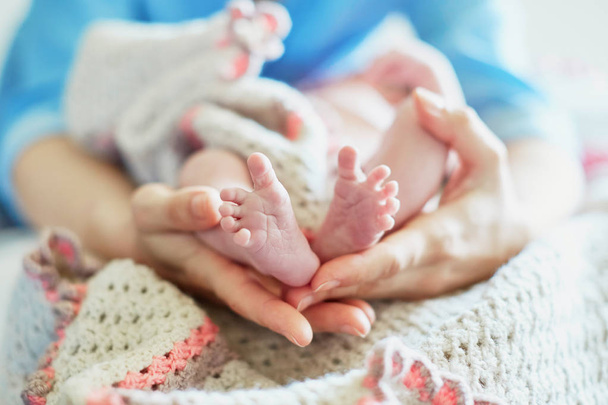 Mother holding newborn baby's feet in her hands - Фото, зображення
