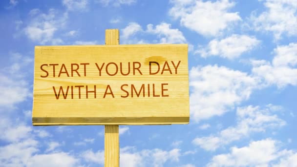 Inizia la giornata con un sorriso parole su un segno di legno contro le nuvole time lapse nel cielo blu
  - Filmati, video