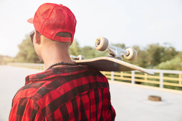 Young dark skinned guy holding skateboard - Foto, Imagen