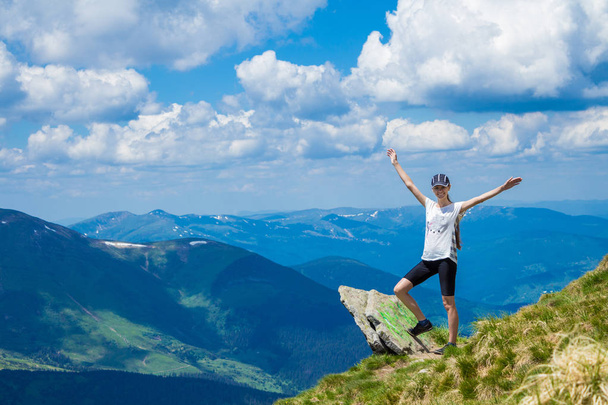 Νεαρή γυναίκα τουριστικά στην άκρη του βράχου των βουνών αυξήσει το χέρι - Φωτογραφία, εικόνα