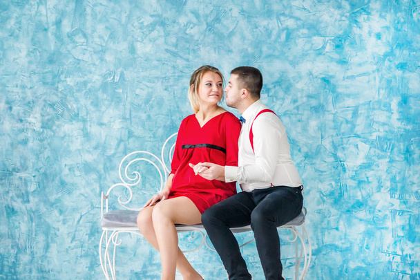 Milující se mladý pár sedí na lavičce, při pohledu na sebe a navzájem dotýkají na lavičce. Muž a žena sedící na lavičce. Studio natáčení - Fotografie, Obrázek