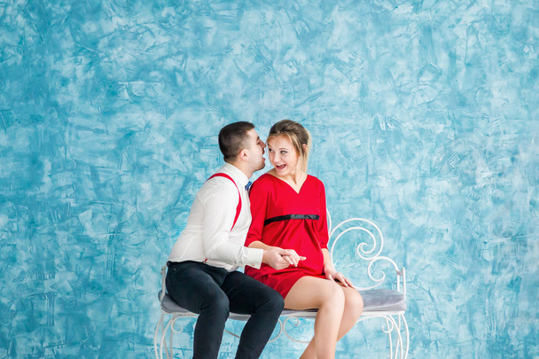 Αγαπώντας το νεαρό ζευγάρι κάθεται σε ένα παγκάκι, βλέπουν ο ένας τον άλλον και επαφή μεταξύ τους σε ένα παγκάκι. Άνδρας και γυναίκα που κάθεται σε ένα παγκάκι. Studio γυρίσματα - Φωτογραφία, εικόνα