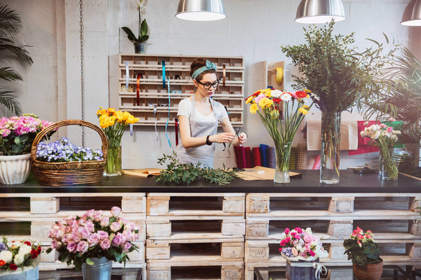 Cute concentrated female florist working in flower shop - Foto, Imagen