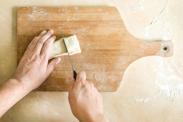 Mens hands cutting raw dough - Photo, Image