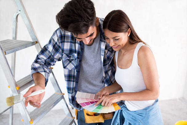 Jeune couple choisissant des couleurs pour peindre leur maison
 - Photo, image
