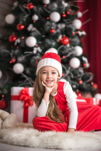 Portrait of a cute little girl on a christmas tree background. - Foto, Imagem