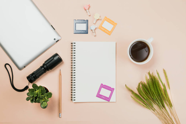 Plat leggen leeg boek en potlood, tablet voor ontwerpwerk met zaklamp, een koffiekopje en een kleine cactus op gele pastel kleur achtergrond. - Foto, afbeelding