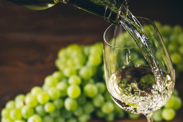 Pouring white wine into a glass  - Фото, изображение