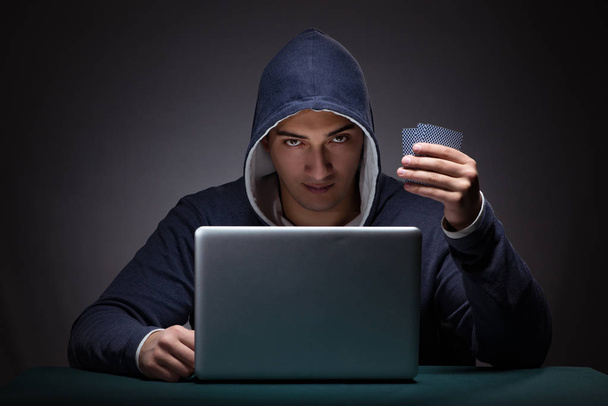 Young man wearing a hoodie sitting in front of a laptop computer - Foto, imagen