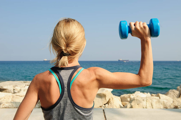 Strong young woman doing shoulder press with dumbell Stock Photo