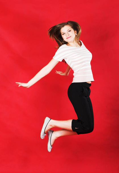 girl jumping of joy over red - Foto, Imagen