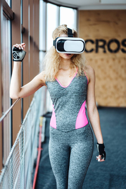 Piękna dziewczyna na siłowni z zestawem słuchawkowym VR - Zdjęcie, obraz