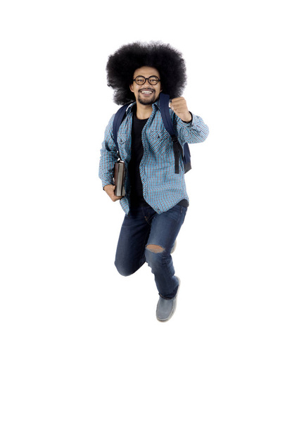 African male student jumping in the studio - Фото, зображення