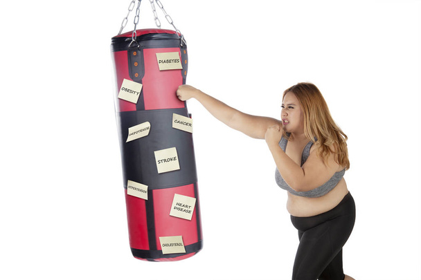 Fat woman punching her diseases on studio - Foto, immagini