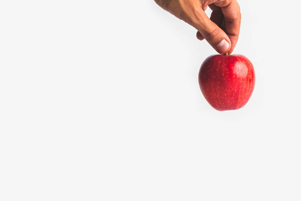 крупный план руки, держащей свежее красное яблоко на белом берегу
 - Фото, изображение