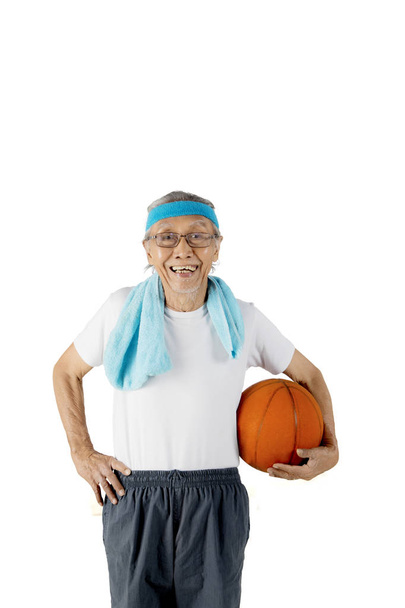 Old man carrying a basketball on studio - Foto, afbeelding