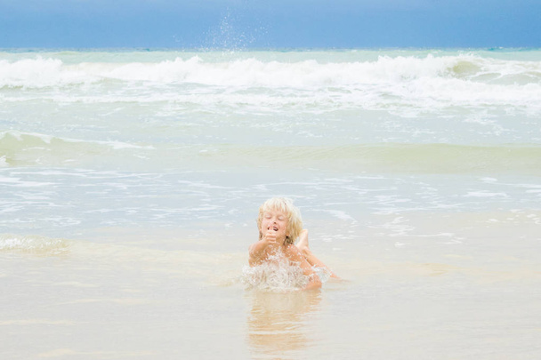 A happy blond boy lies in a water on a  beach, Vietnam, Nha-trang - Fotografie, Obrázek