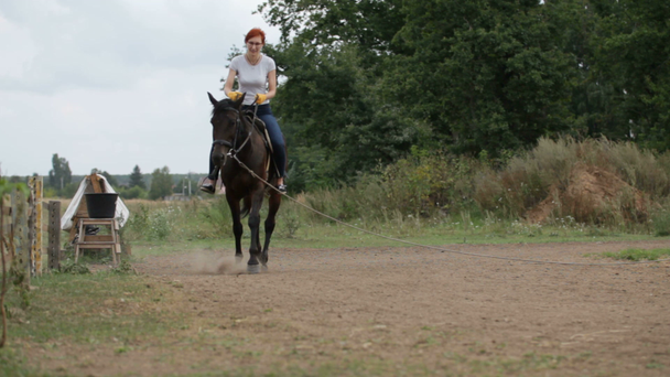 Červené vlasy dívka jezdí na koni ve dne - jezdecké lekce - Záběry, video