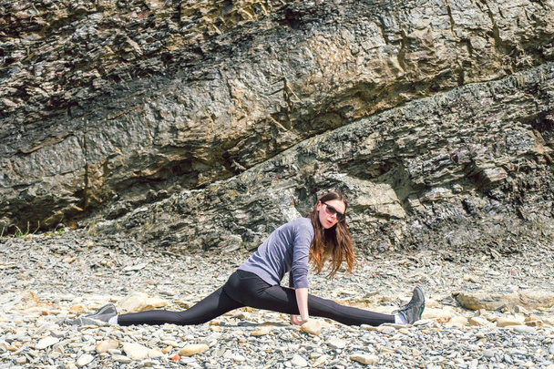 Boční pohled na obrázek Zdravá dospělá žena, strečink a cvičení na skalní plošině - Fotografie, Obrázek