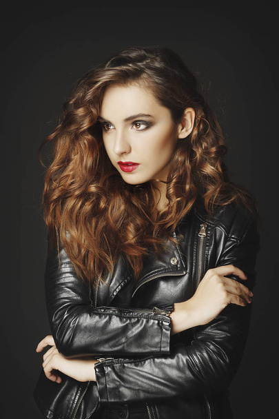Beautiful young woman posing in black leather jacket over grey b - Photo, Image