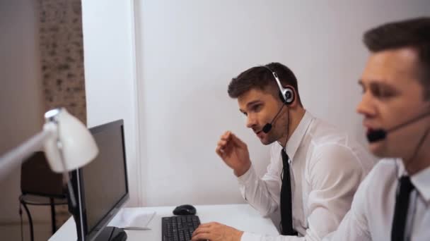 Dva specialisté technické podpory mluvit se zákazníky po sluchátkách. - Záběry, video