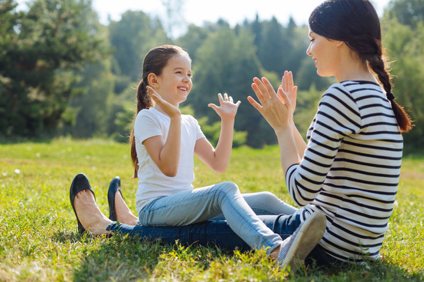 Happy daughter playing pat-a-cake with her mother outdoors - Foto, afbeelding