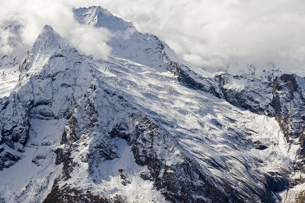 Peaks and glaciers in caucasus mountains by winter covered by snow with cloudy sky above them. - Foto, Bild