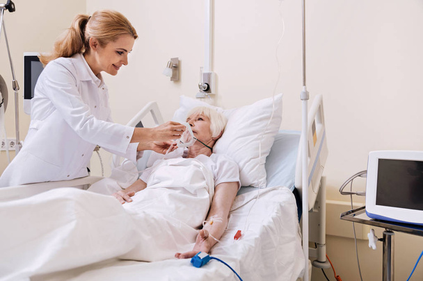 Sweet professional doctor taking care of aged patient - Photo, image