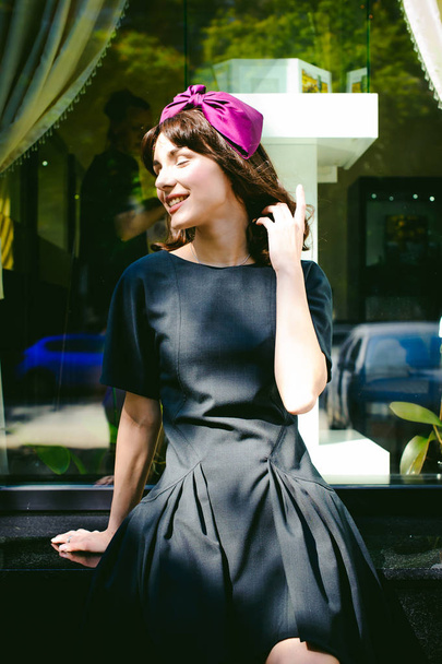 Beautiful woman in a dark stylish dress strolls along the street, near boutiques. Portrait of a fashionable girl - Fotó, kép