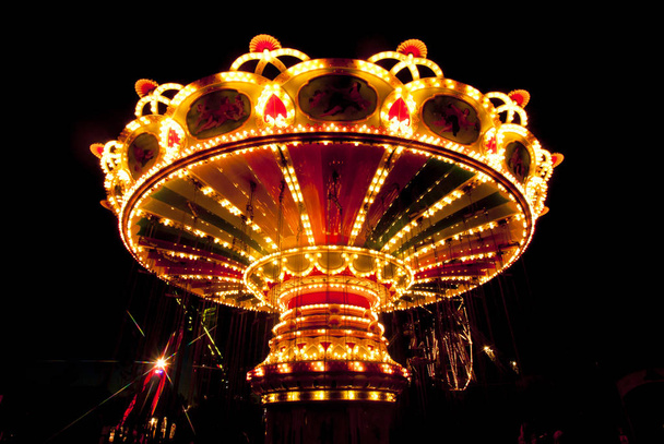 Colorido carrusel oscilación de la cadena en movimiento en el parque de atracciones por la noche
. - Foto, Imagen