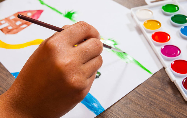 The child's hand draws a picture with watercolors - Fotó, kép