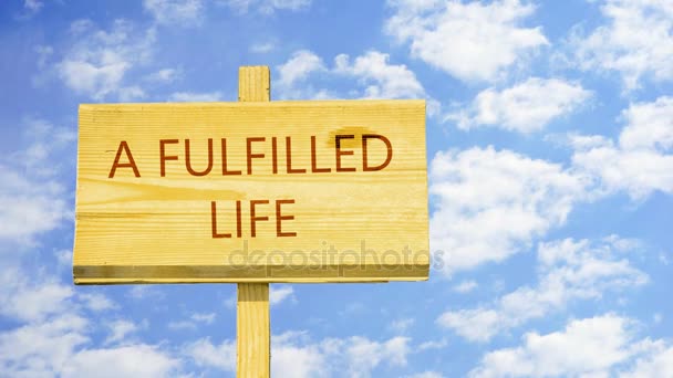 A fulfilled life. Words on a wooden sign against time lapse clouds in the blue sky.  - Footage, Video