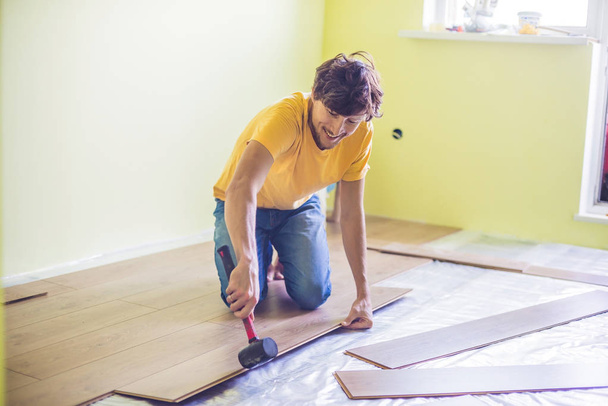 Man installing new wooden laminate flooring - Foto, imagen